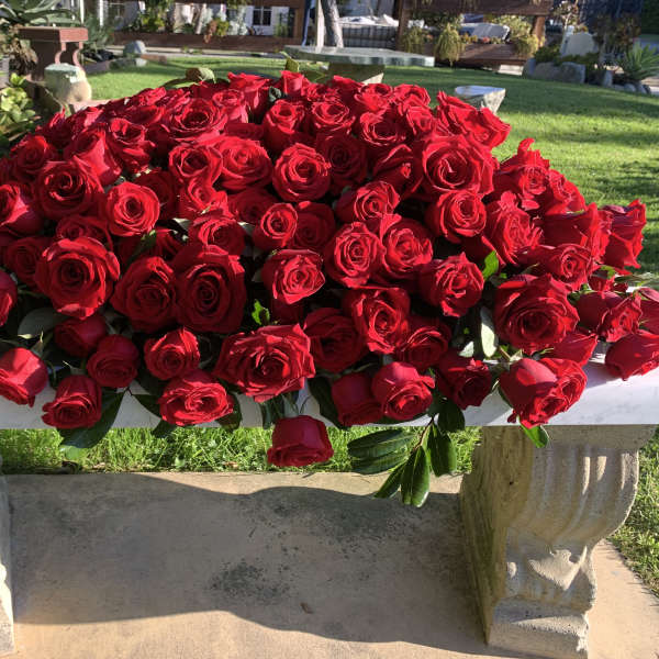 Large mound of red roses on a stone bench outdoors