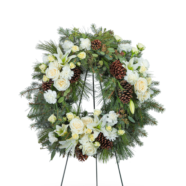 White floral wreath with roses, lilies, and pinecones on a stand