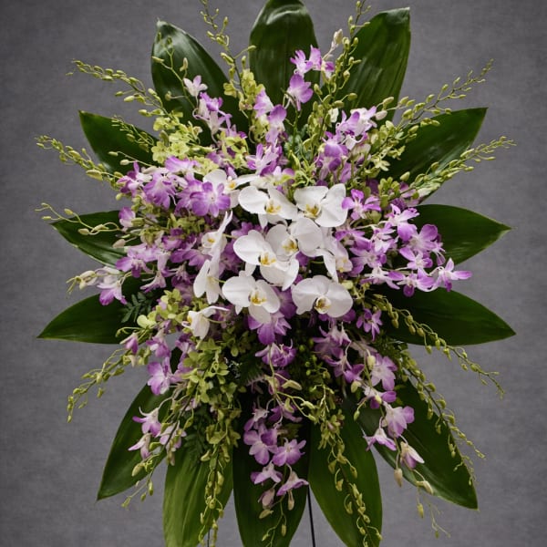 Standing floral spray with white and purple orchids on a metal easel