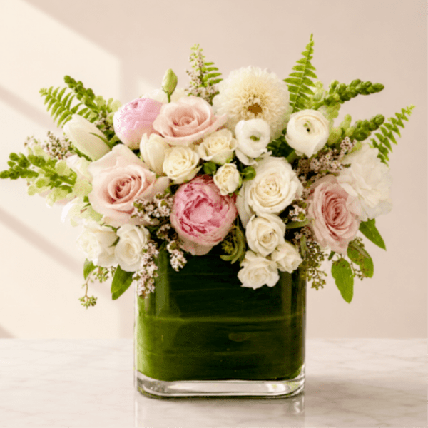 Pink and white roses with ranunculus in a square glass vase