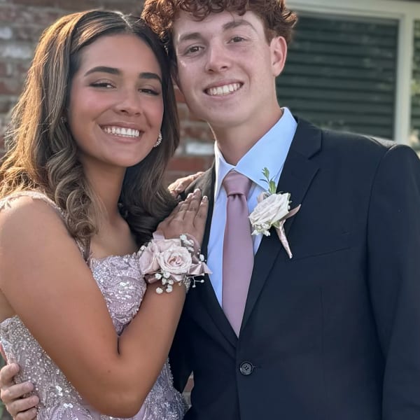 Couple in formal attire wearing matching blush rose wrist corsage and boutonniere