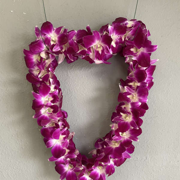 Heart-shaped purple orchid lei hanging on a wall