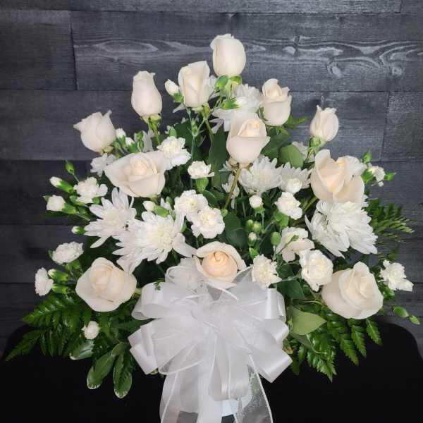 White roses and chrysanthemums arranged with a white ribbon bow