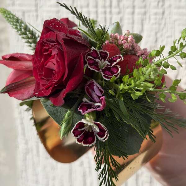 Red rose and pink blooms wrist corsage on a gold metal cuff bracelet