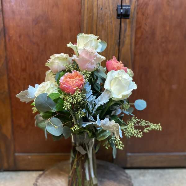 Bouquet of pale roses and coral blooms in a glass vase