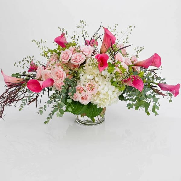 Pink roses and calla lilies arranged in a clear glass vase