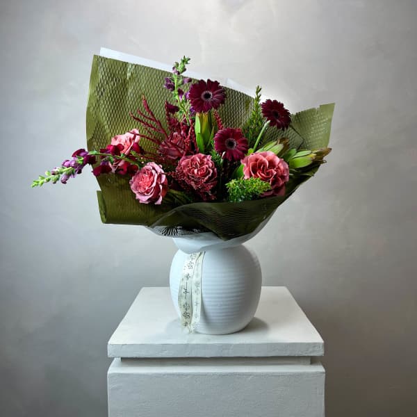 Bouquet of pink and burgundy flowers in a white vase