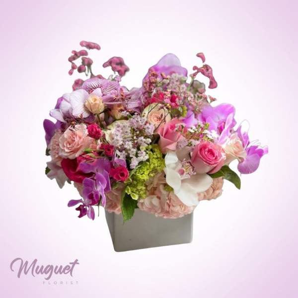 Pink and purple floral arrangement in a gray square vase