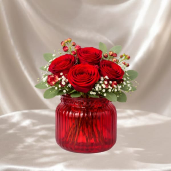 Red roses arranged in a red glass vase