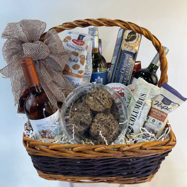 Gift basket with wine, snacks, and cookies in a wicker basket