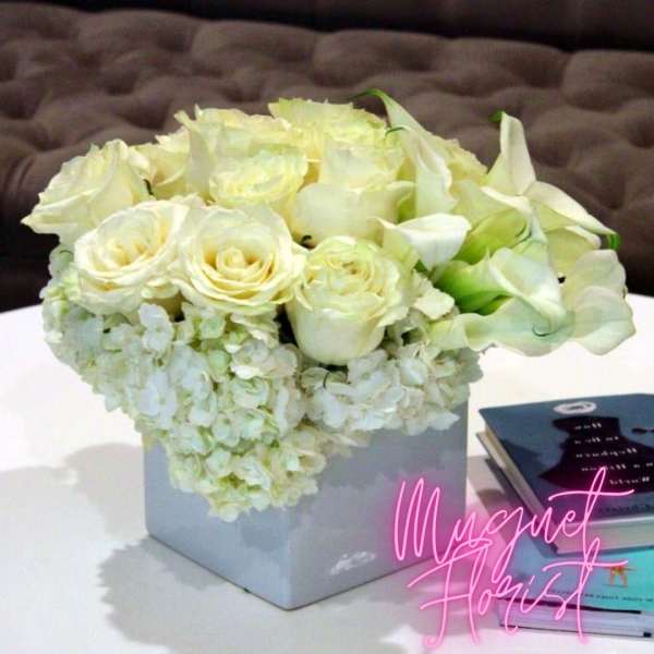 White roses and calla lilies arranged in a square box