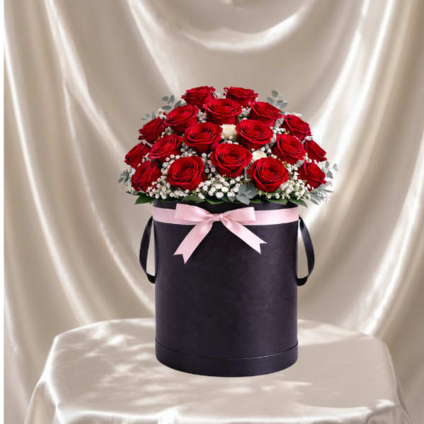 Red roses in a black hatbox with a pink ribbon