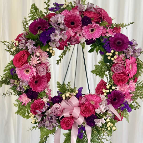 Heart-shaped floral wreath with pink and purple flowers on a stand
