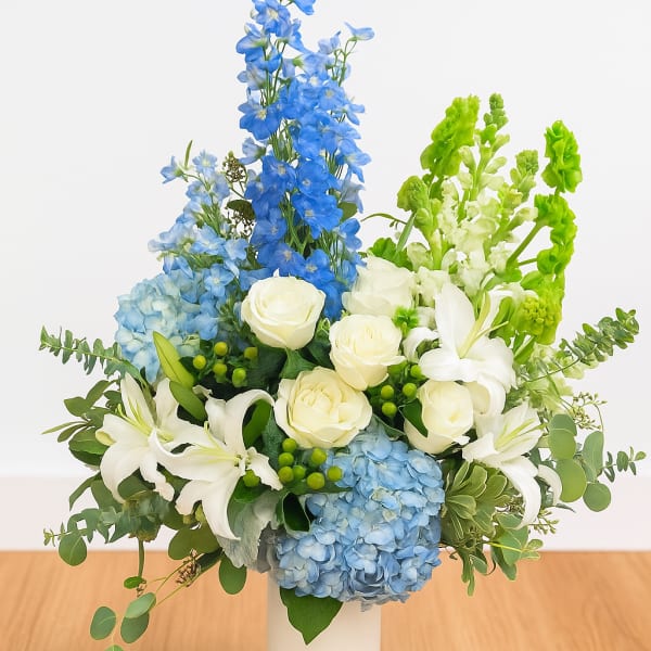 Blue and white floral arrangement in a white vase