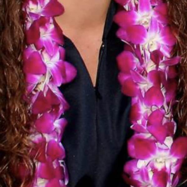 Pink orchid lei draped around a person wearing a black top