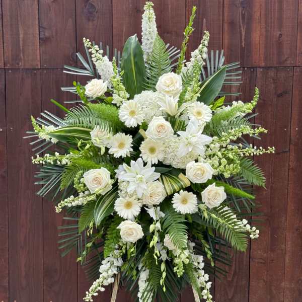 White floral standing spray with roses and lilies on an easel