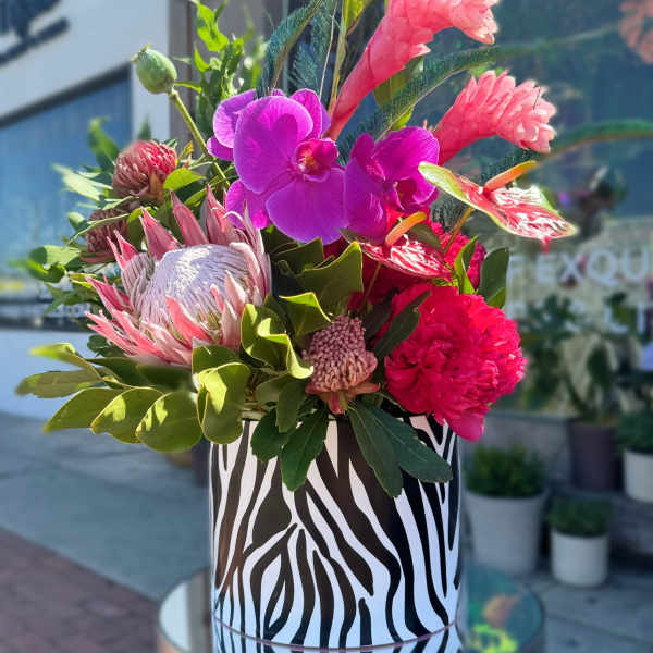 Tropical bouquet in a zebra-print vase with pink and purple blooms