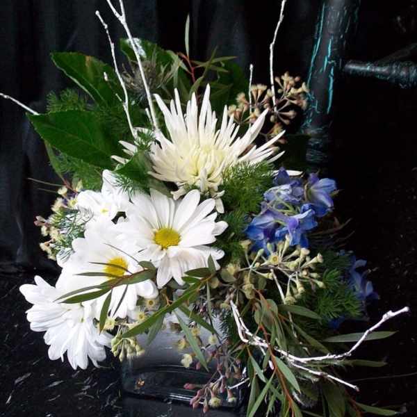 Bouquet of white daisies and blue flowers with greenery