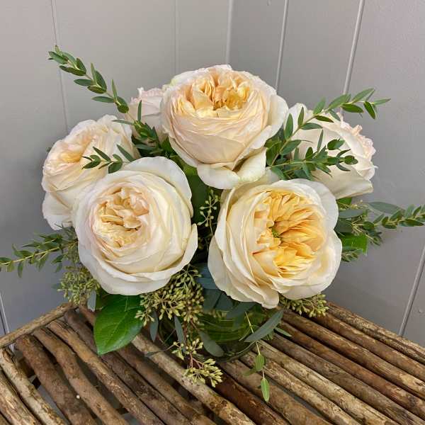 Bouquet of cream and pale peach roses with greenery in a glass vase