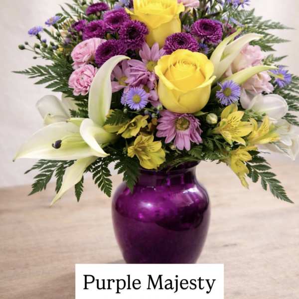 Mixed bouquet of yellow roses, purple daisies, and white lilies in a purple vase
