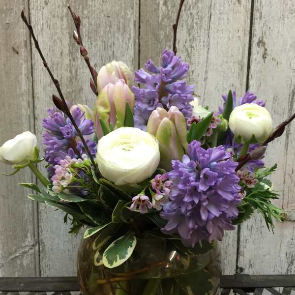 Purple and white flowers arranged in a round glass vase