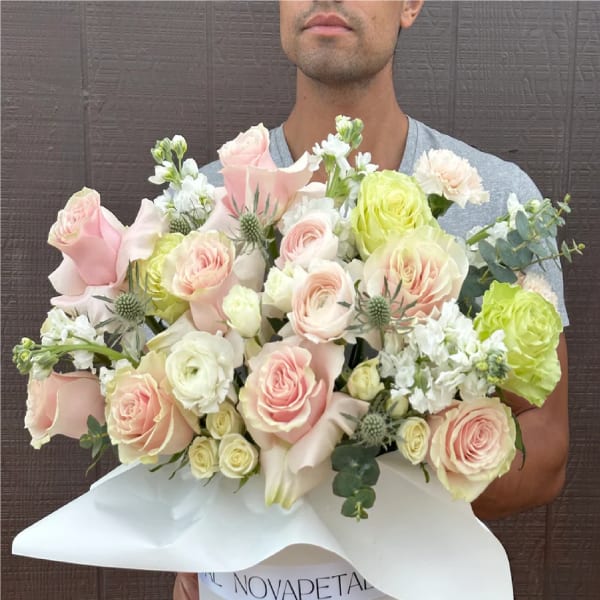 Bouquet of pale pink and white roses with white blooms in white wrap