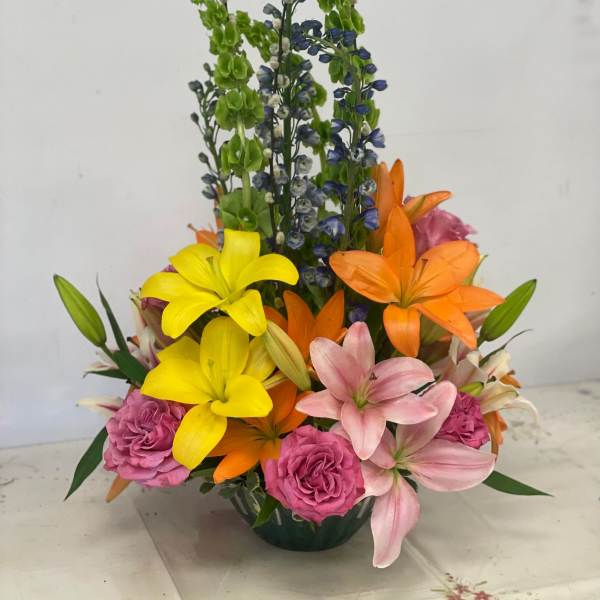 Colorful mixed bouquet with lilies and roses in a low vase