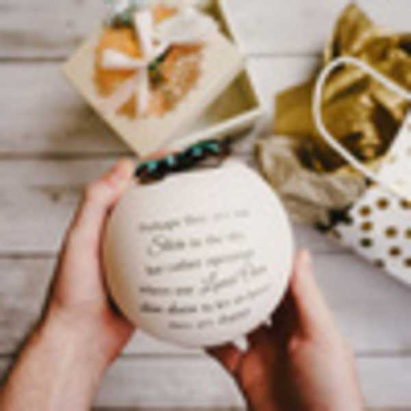 Hands holding a round white gift box with a printed message