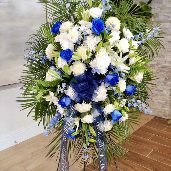 Large standing floral spray with blue and white flowers on an easel