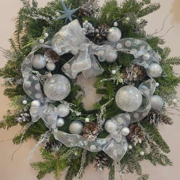 Christmas wreath with silver ornaments, pinecones, and a sheer ribbon