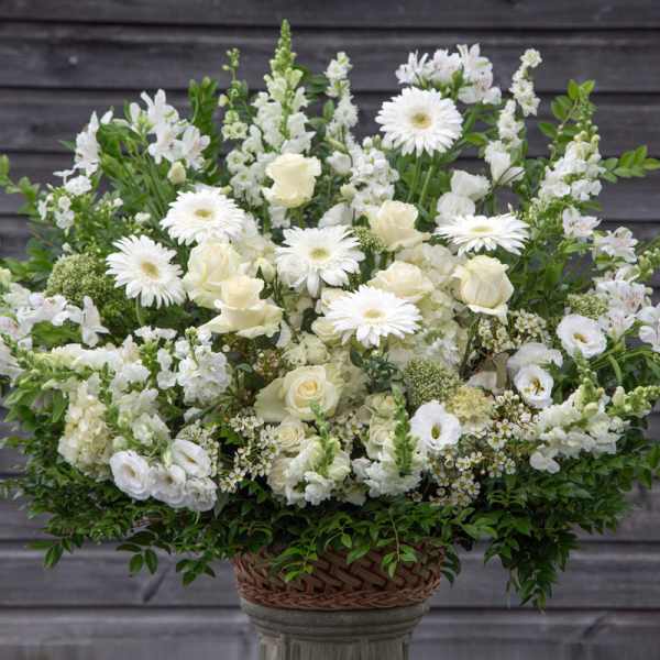 White floral arrangement in a woven basket on a pedestal