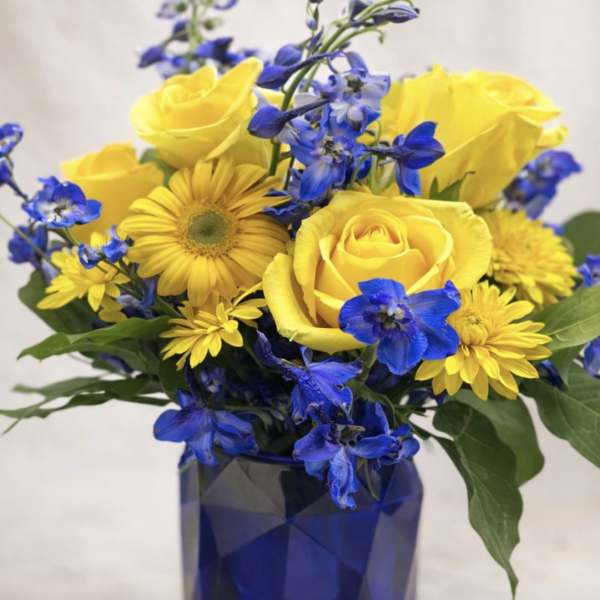 Yellow roses and blue flowers in a blue vase