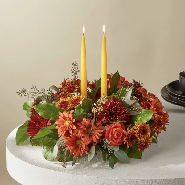 Round floral centerpiece with two yellow taper candles
