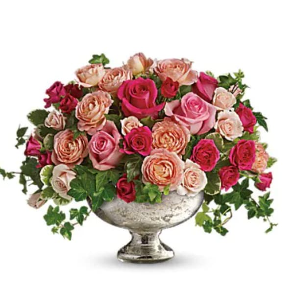 Pink and peach roses arranged in a silver pedestal vase