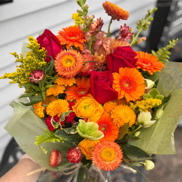 Bouquet of orange and red flowers wrapped in green paper