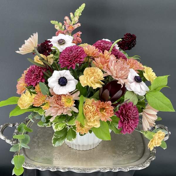 Mixed bouquet of chrysanthemums, carnations, and anemones in a white vase
