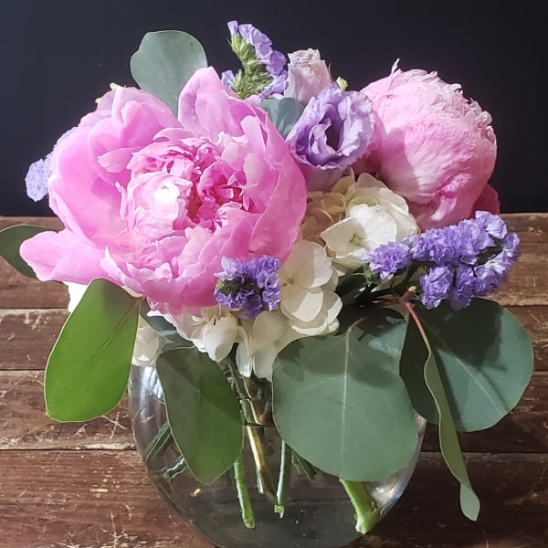 Pink and lavender flowers arranged in a clear glass vase