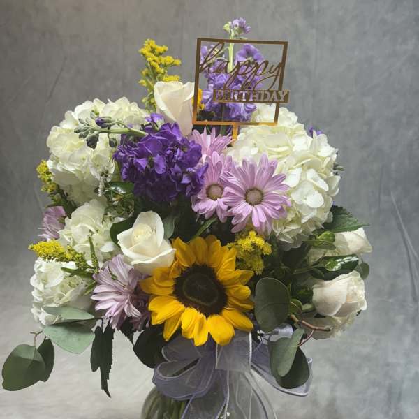 Mixed bouquet in a glass vase with a happy birthday sign