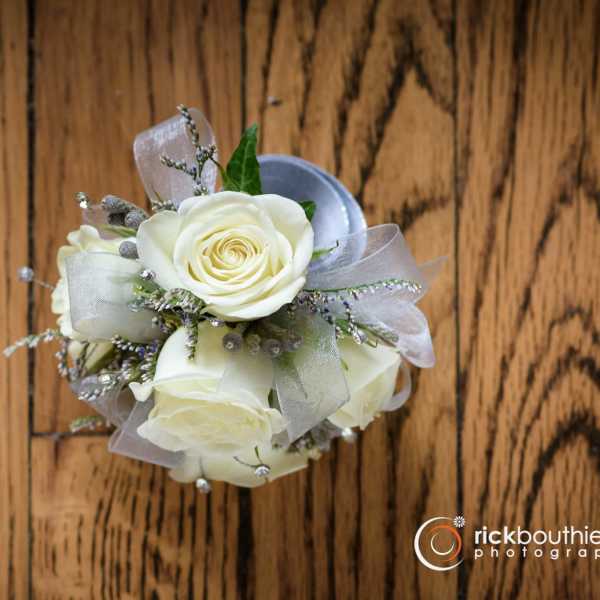 Small bouquet of white roses with silver ribbon on a wood surface