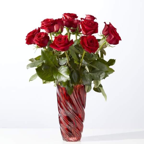 Red roses arranged in a tall red glass vase