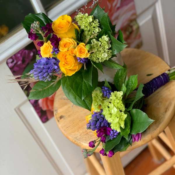 Two colorful hand-tied bouquets with yellow roses and purple flowers