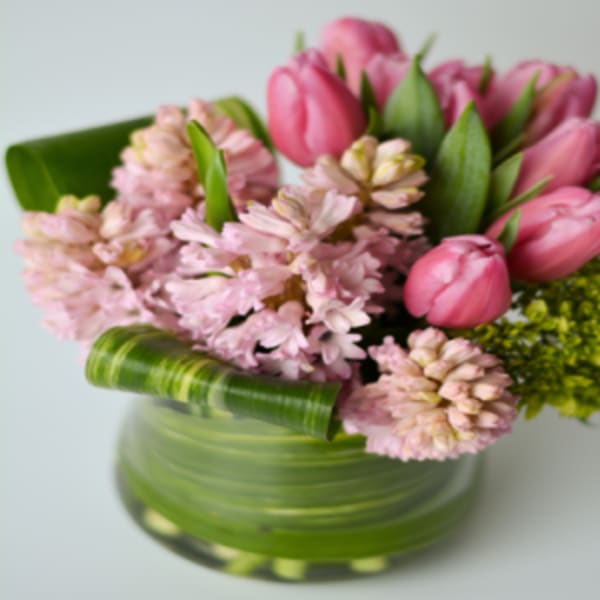 Pink tulips and pale pink flowers in a green glass vase