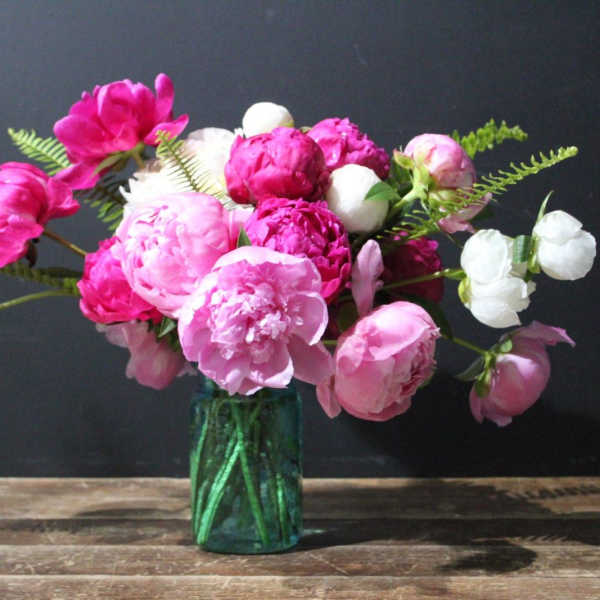 Pink and white peonies in a green glass vase