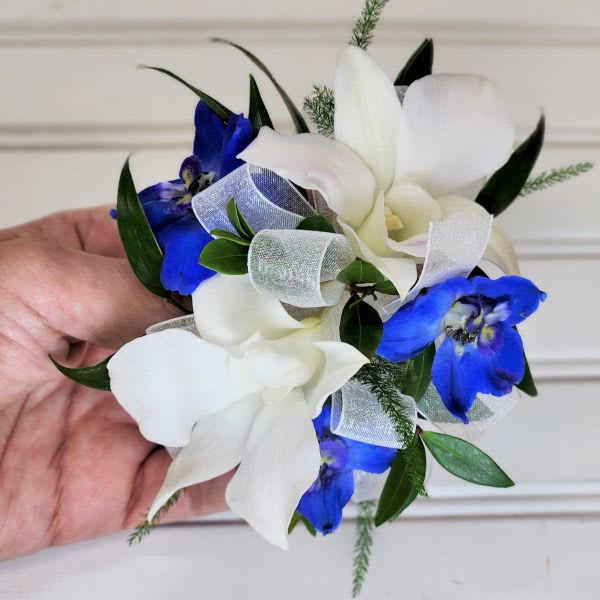 Small white and blue floral corsage with ribbon
