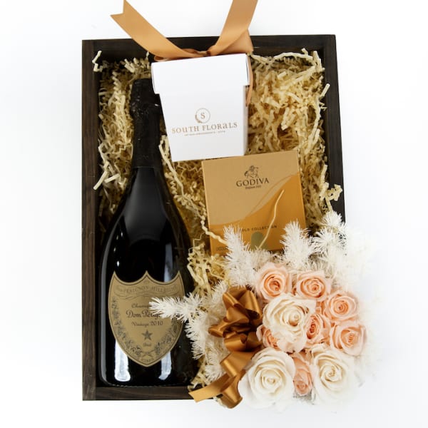 Gift box with champagne bottle, chocolates, and small peach and white rose bouquet