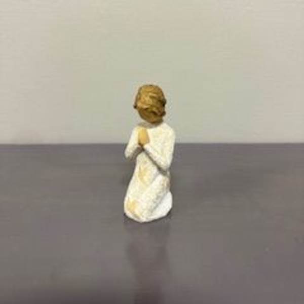 Small angel figurine in a white robe standing on a table