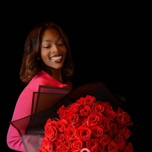 Woman holding a large bouquet of red roses wrapped in black paper
