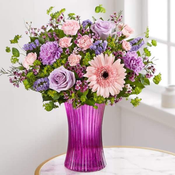 Mixed pink and lavender flowers in a tall purple vase