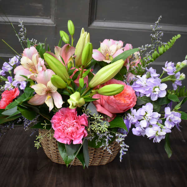 Basket arrangement of pink lilies, roses, and purple flowers
