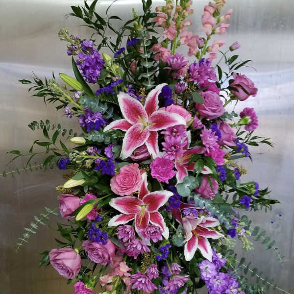 Tall pink and purple floral spray with lilies and roses on an easel